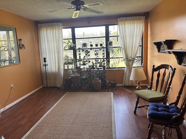 living area featuring ceiling fan, wood finished floors, baseboards, and a textured ceiling