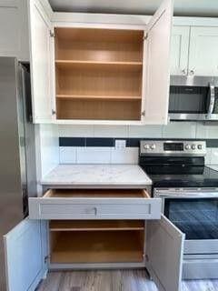 interior space featuring open shelves, light wood-style floors, and appliances with stainless steel finishes