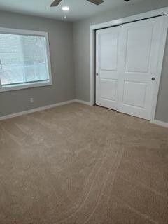 unfurnished bedroom with carpet flooring, a ceiling fan, baseboards, and a closet