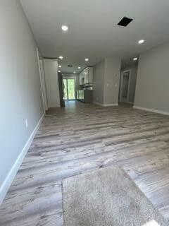 unfurnished living room with recessed lighting, baseboards, and wood finished floors