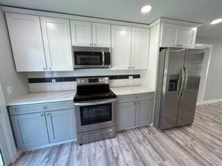 kitchen with light countertops, white cabinets, light wood finished floors, and stainless steel appliances