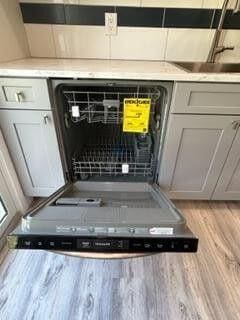 interior details featuring light countertops, light wood-type flooring, dishwashing machine, and a sink