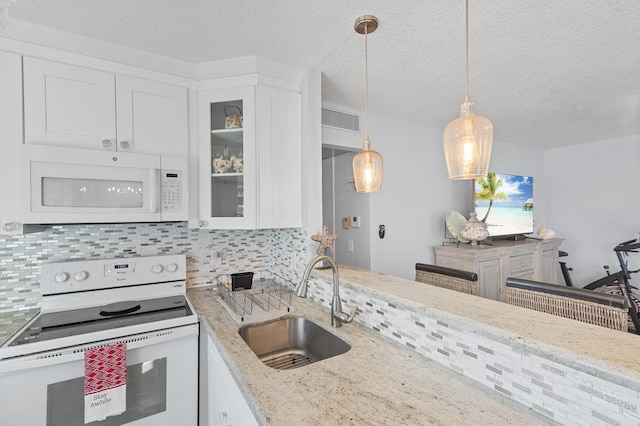 kitchen with decorative backsplash, white appliances, visible vents, and a sink