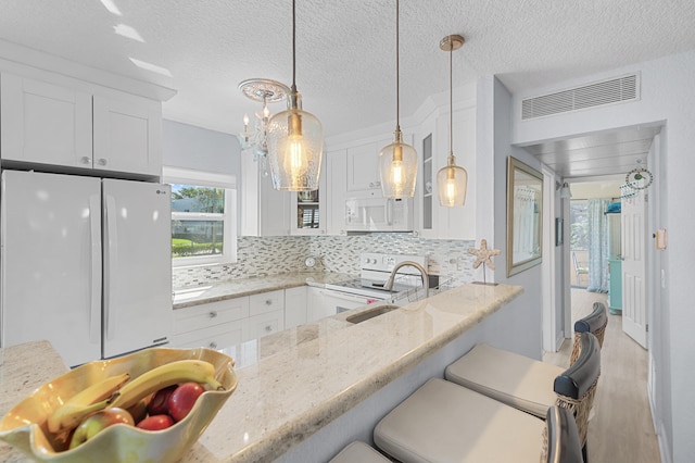 kitchen featuring tasteful backsplash, visible vents, pendant lighting, white appliances, and white cabinetry