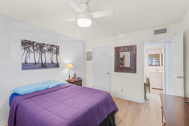 bedroom featuring visible vents, baseboards, light wood-type flooring, a ceiling fan, and a sink