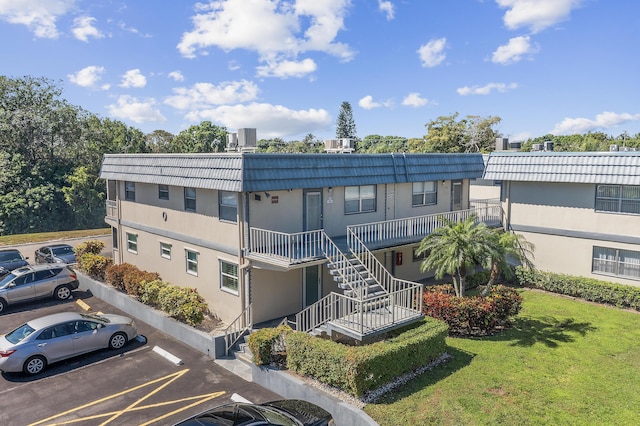 view of property featuring stairway, central air condition unit, and uncovered parking