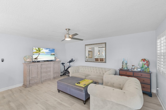 living room with a textured ceiling, light wood-type flooring, baseboards, and a ceiling fan