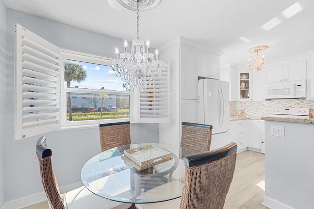 dining area with a textured ceiling, baseboards, light wood finished floors, and a chandelier