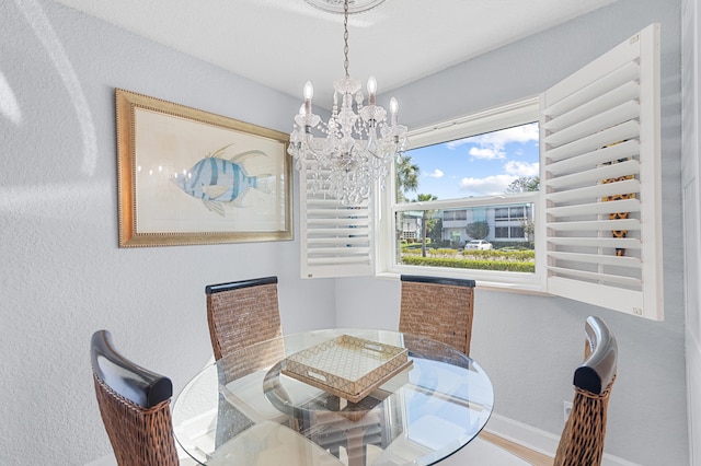 dining room with an inviting chandelier, wood finished floors, baseboards, and a textured wall