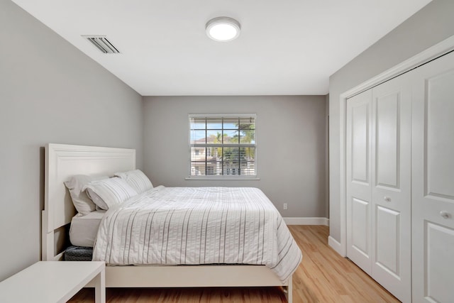 bedroom featuring baseboards, visible vents, light wood-style flooring, and a closet