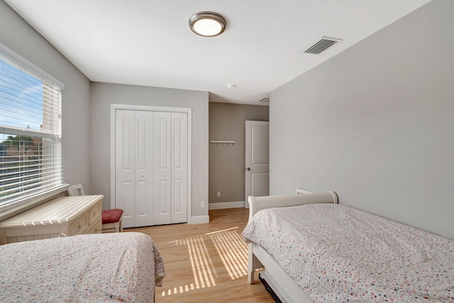 bedroom featuring light wood-style floors, baseboards, a closet, and visible vents