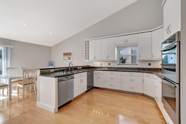 kitchen with plenty of natural light, a sink, a peninsula, stainless steel appliances, and light wood-style flooring