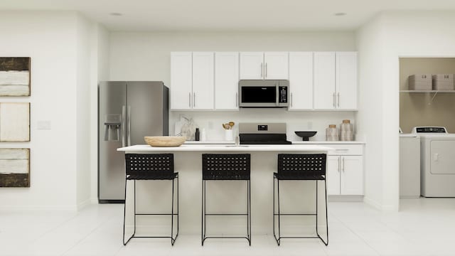 kitchen featuring washer and dryer, stainless steel appliances, a center island with sink, and white cabinetry