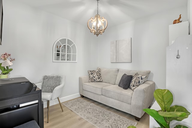 living area with baseboards, a notable chandelier, and wood finished floors