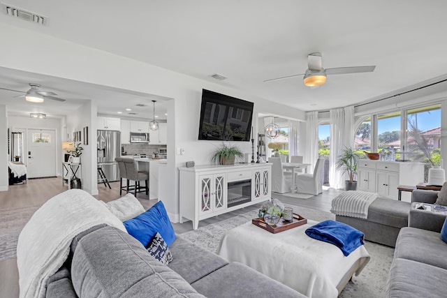 living area with visible vents, light wood finished floors, and ceiling fan