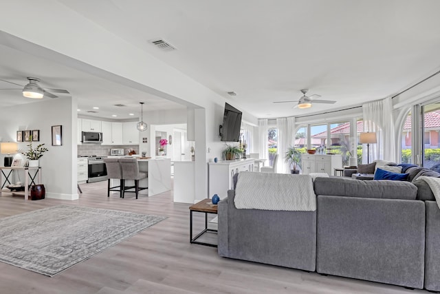 living area with visible vents, a ceiling fan, recessed lighting, light wood-style floors, and baseboards