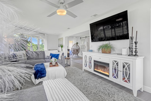 living area with visible vents, wood finished floors, and a ceiling fan