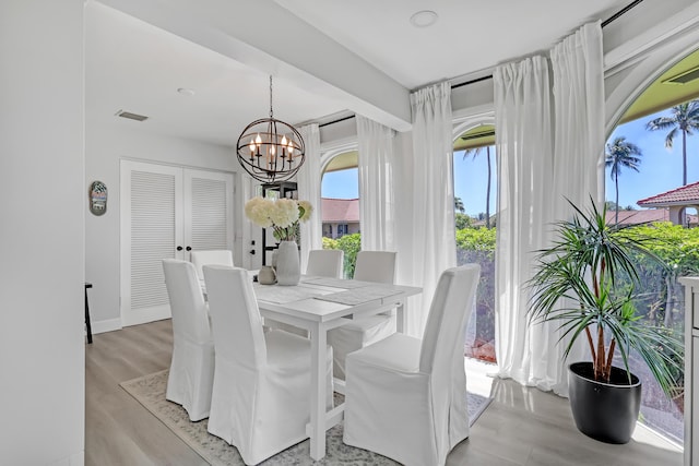 dining room with visible vents, light wood-style floors, and an inviting chandelier