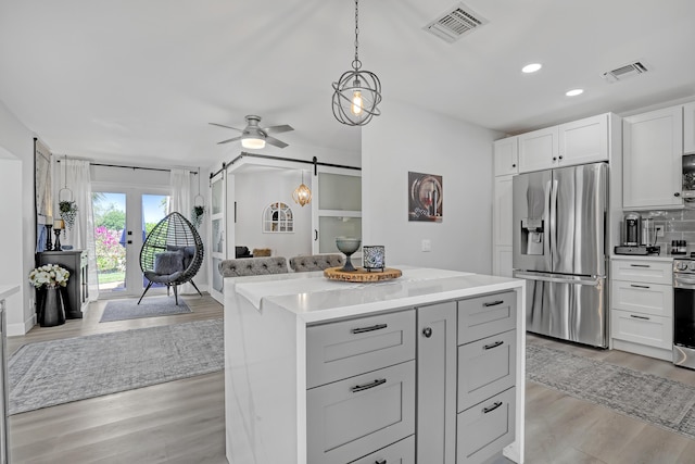 kitchen featuring visible vents, a barn door, appliances with stainless steel finishes, and light countertops