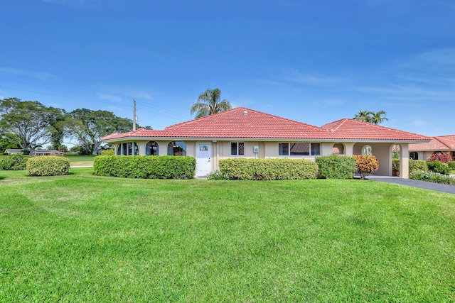 view of front of home featuring a front lawn, a tiled roof, and stucco siding