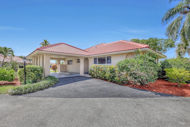 mediterranean / spanish home with aphalt driveway, stucco siding, and a tiled roof