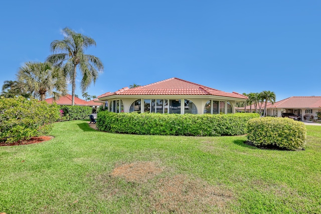 rear view of property featuring a yard, stucco siding, and a tiled roof