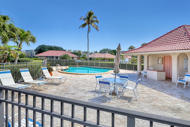pool with a patio, an outdoor kitchen, and fence