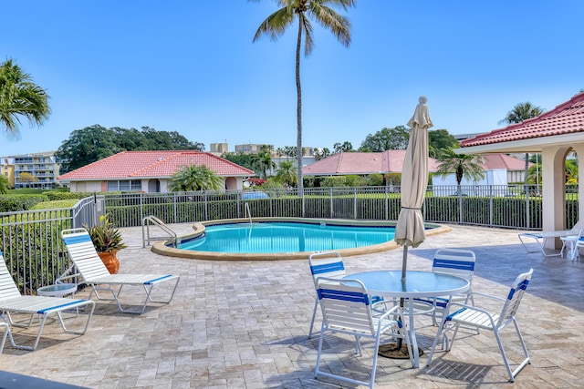 community pool with a patio area and fence