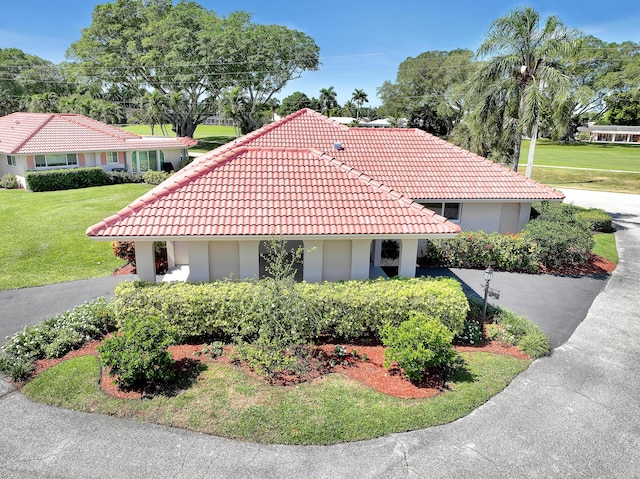 view of front of property with a front lawn, a tile roof, and stucco siding