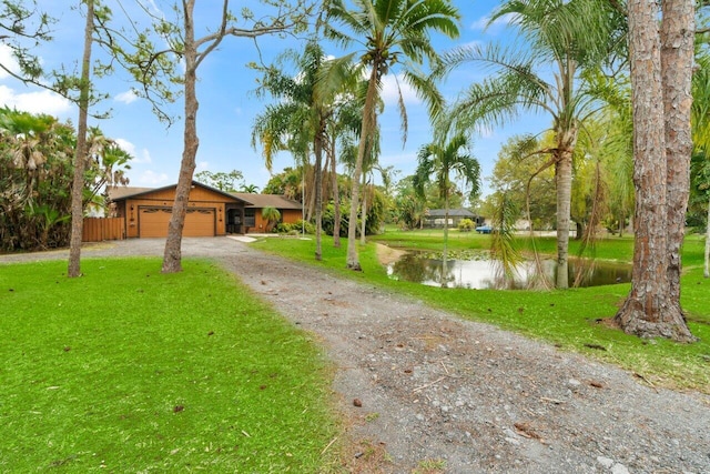 view of front facade featuring a water view, a front lawn, dirt driveway, fence, and a garage