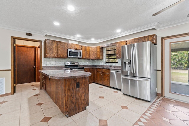 kitchen featuring a sink, tasteful backsplash, dark countertops, stainless steel appliances, and a healthy amount of sunlight