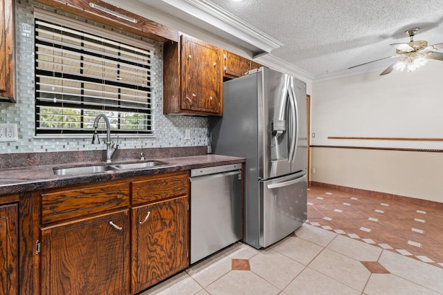 kitchen with light tile patterned floors, ornamental molding, appliances with stainless steel finishes, and a sink