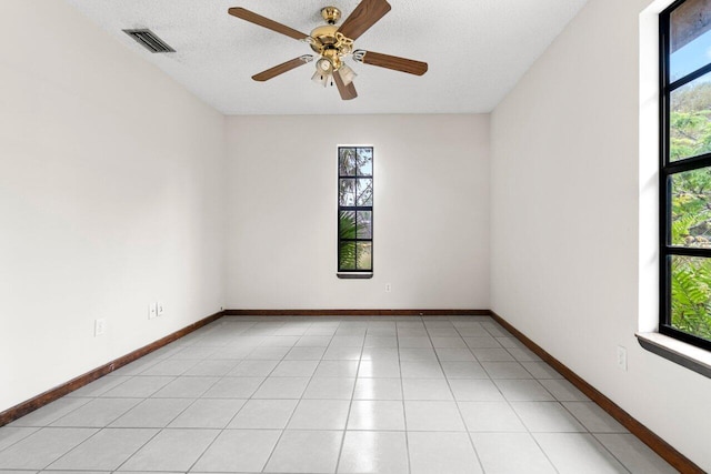 empty room featuring visible vents, baseboards, light tile patterned flooring, a textured ceiling, and a ceiling fan