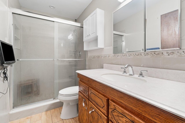 full bath with vanity, toilet, tile walls, and a shower stall