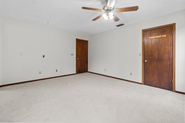 spare room with visible vents, light carpet, a textured ceiling, and baseboards