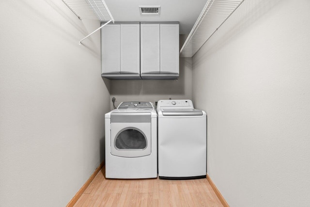 laundry area featuring baseboards, visible vents, light wood-style flooring, cabinet space, and washer and clothes dryer