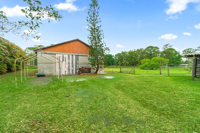 view of yard featuring an outbuilding, fence, a garage, and a pole building