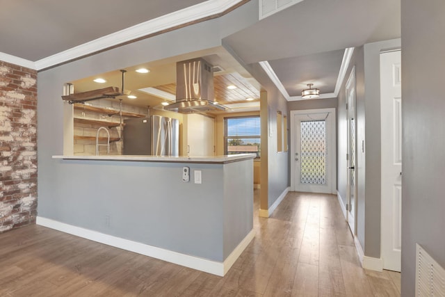 kitchen featuring light wood finished floors, island exhaust hood, freestanding refrigerator, and ornamental molding