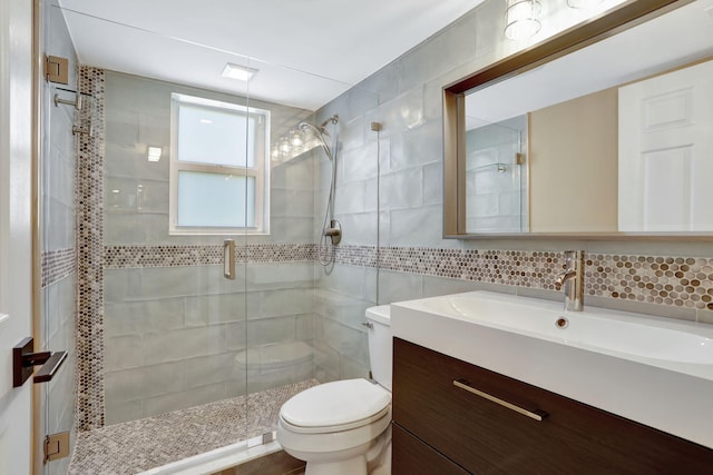 full bath featuring a shower stall, tile walls, toilet, decorative backsplash, and vanity