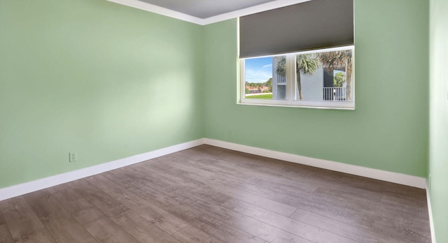 unfurnished room with wood finished floors, baseboards, and ornamental molding