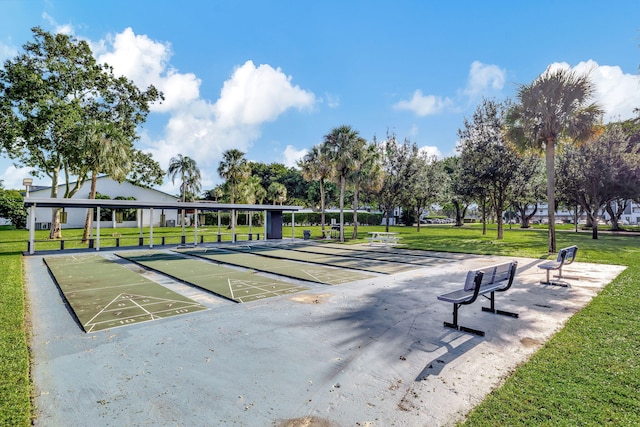 view of home's community with shuffleboard and a yard