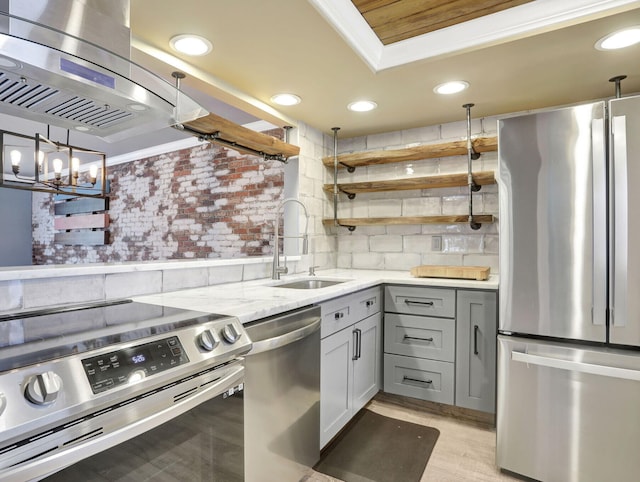 kitchen featuring island exhaust hood, a sink, gray cabinetry, open shelves, and appliances with stainless steel finishes