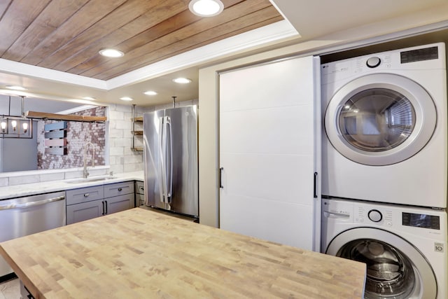 interior space with stacked washer and dryer, a sink, recessed lighting, stainless steel appliances, and wooden ceiling