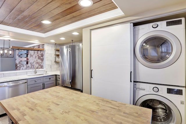 laundry area with a sink, wooden ceiling, stacked washer and dryer, laundry area, and recessed lighting
