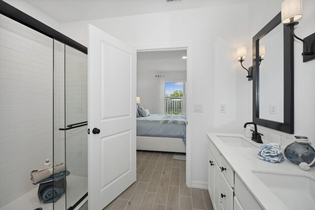 full bathroom featuring a sink, connected bathroom, wood finish floors, and a stall shower