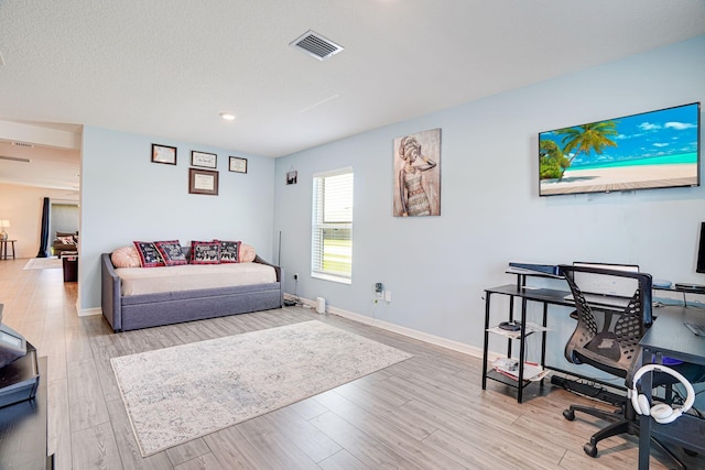 living room with visible vents, baseboards, a textured ceiling, and wood finished floors