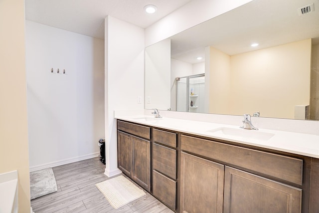 bathroom featuring double vanity, visible vents, a stall shower, and a sink