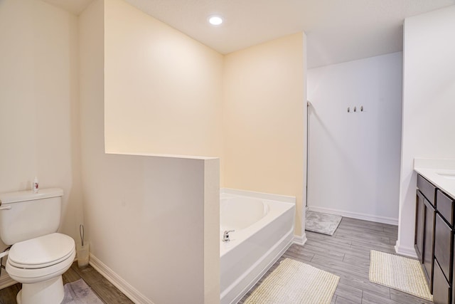 bathroom with wood finish floors, baseboards, toilet, and a bath