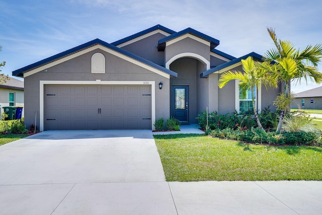 single story home with a front yard, an attached garage, driveway, and stucco siding