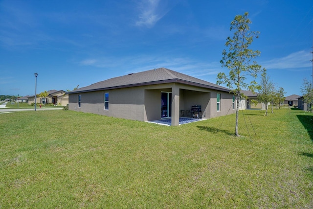 rear view of house with a yard, a patio area, and stucco siding